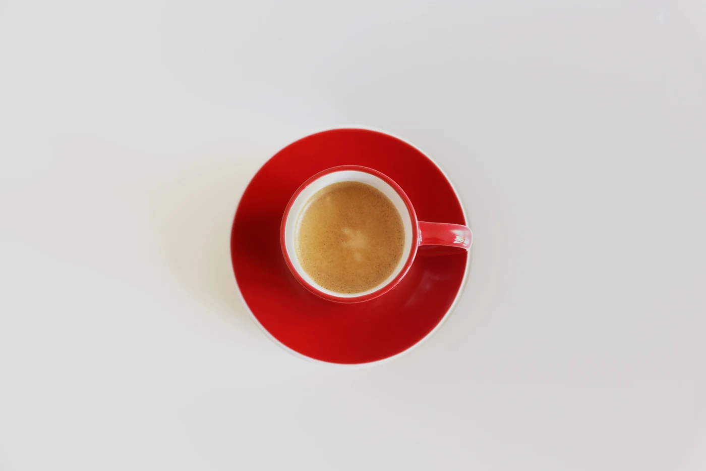 An overhead photograph of coffee in a red cup