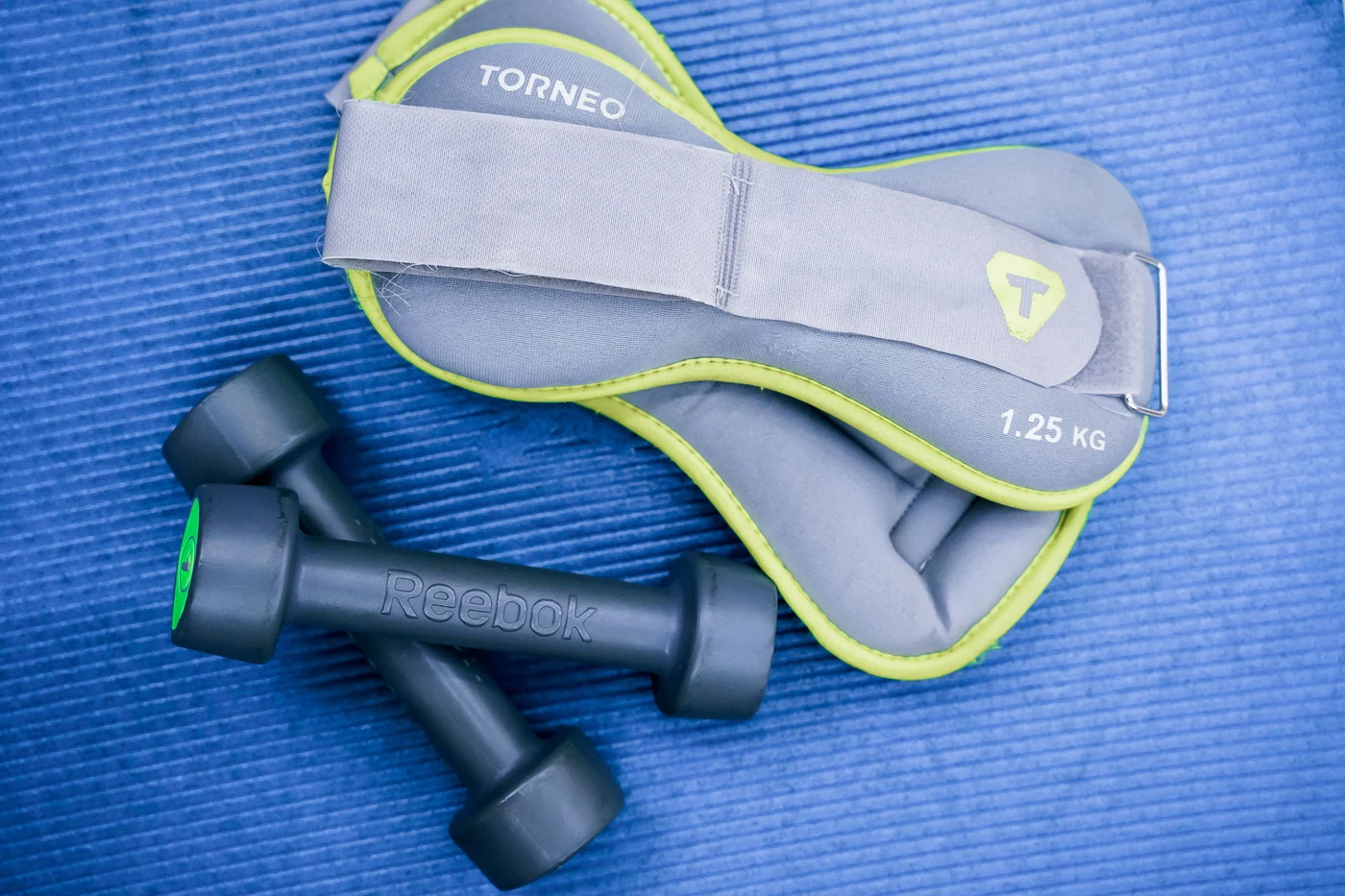 Light dumbbells and ankle weights on an exercise mat