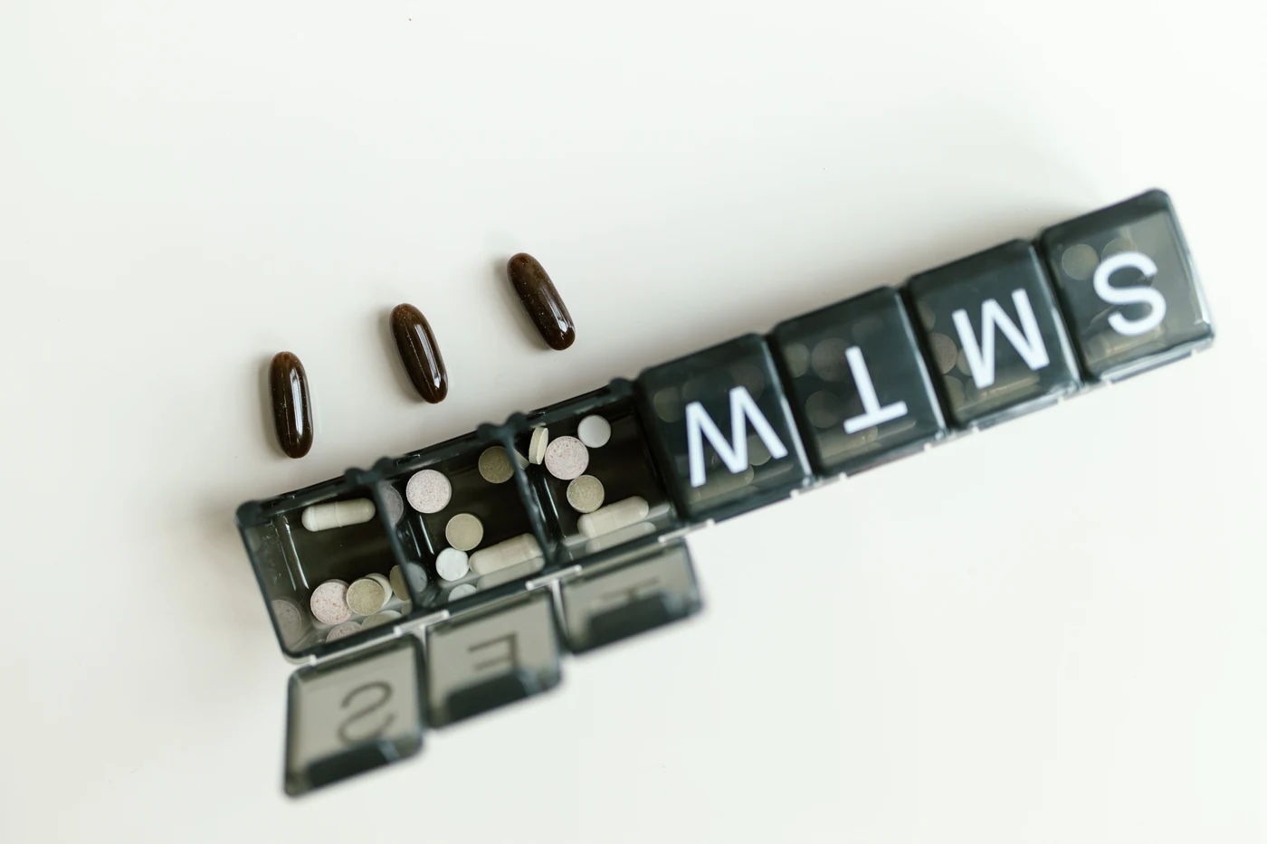Pills and capsules beside a weekly organizer